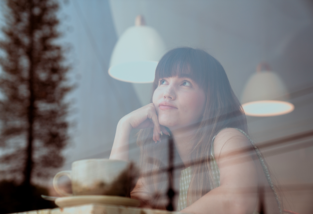 Mujer pensativa mirando por la ventana, reflexión sobre la vida y la realidad que creamos.