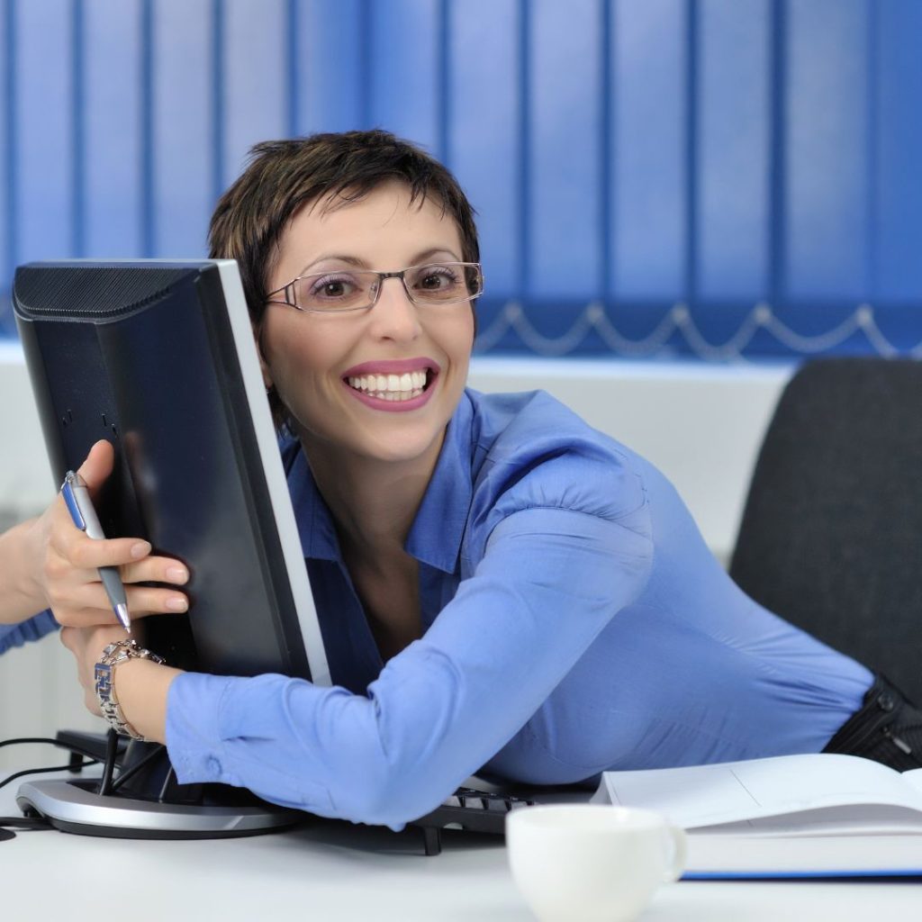 Mujer abrazando un monitor con una gran sonrisa, representando el vínculo emocional que algunas personas proyectan en la tecnología.