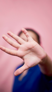 Mujer con la mano al frente en gesto de "basta" a la violencia.