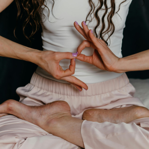 Mujer meditando en posición de loto haciendo mudra de manos, ilustrando la práctica de mantras y respiración para calmar la ansiedad.