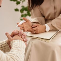 Psicóloga en sesión de terapia individual em Barcelona con una mujer, tomando notas mientras la paciente se expresa