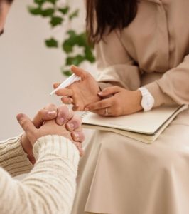 Psicóloga en sesión de terapia individual em Barcelona con una mujer, tomando notas mientras la paciente se expresa