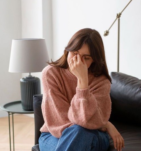 Mujer pensativa sentada en un sillón, simbolizando la resistencia y el proceso de reflexión antes de iniciar terapia